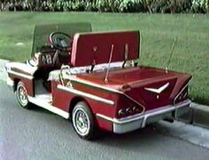 an old red car parked on the side of the road with it's trunk open