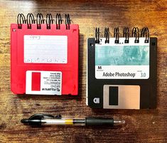 an old floppy disk and pen are next to a notepad on a wooden table