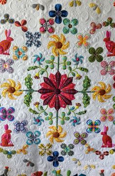 an intricately designed quilt with colorful flowers and butterflies on white fabric, as well as buttons