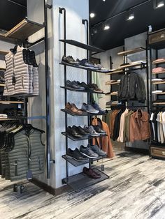 the inside of a men's clothing store with lots of shoes on display and hanging racks