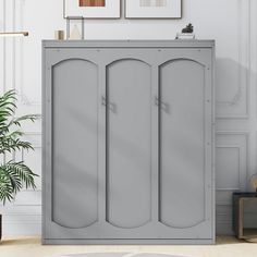 a large gray cabinet sitting in the middle of a living room next to a potted plant