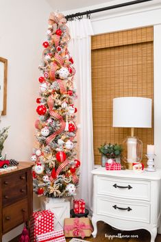 a christmas tree decorated with red and white ornaments in a living room area next to a window