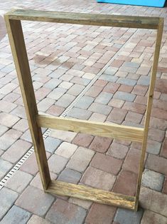 a wooden frame sitting on top of a brick sidewalk