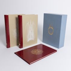 three different colored binders are next to each other on a white surface, one has a ring in the middle