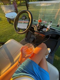 a woman sitting on the back of a golf cart holding a drink in her hand