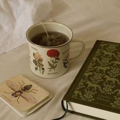 a cup of tea next to a book and coaster