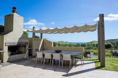 an outdoor dining area with table and chairs next to the fire place in the back yard