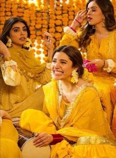 women dressed in yellow sitting on the floor and posing for a photo with each other