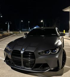 a grey sports car parked in a parking lot next to a gas station at night