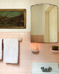 a bathroom with pink tiles and a painting on the wall next to a white sink