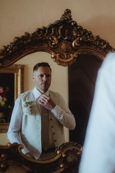 a man in a white shirt and tie is looking at his reflection in the mirror