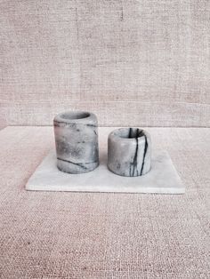 two marble candle holders sitting on top of a rug