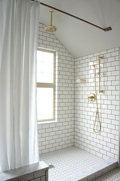 a bathroom with white tile and gold fixtures