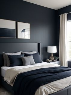 a bedroom with black walls and white bedding, two framed pictures on the wall