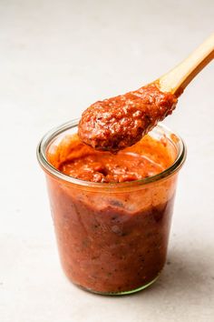 a wooden spoon full of sauce on top of a jar