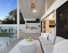 a white couch sitting on top of a wooden floor next to a kitchen and dining area