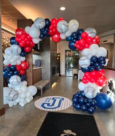 a baseball themed balloon arch in an office lobby with balloons all over the floor and on top of it