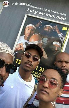 three men standing next to each other in front of a building with a movie poster behind them