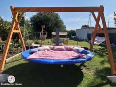 a swing bed in the middle of a yard with a pink and blue blanket on it