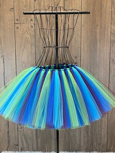 a multicolored tulle skirt hanging on a metal rack in front of a wooden wall