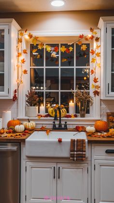 a kitchen decorated for fall with candles and pumpkins on the window sill next to the sink