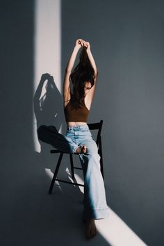 a woman sitting in a chair with her hands behind her head and arms above her head