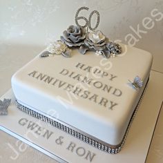 a 60th birthday cake decorated with flowers and pearls on a white tableclothed surface