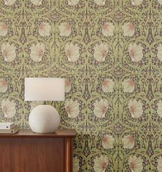 a table with a lamp on it next to a wall paper