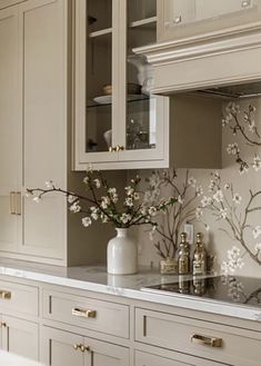 a kitchen with white cabinets and flowers on the counter