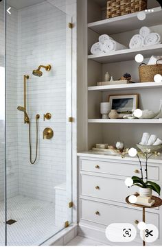 a white bathroom with gold fixtures and shelving