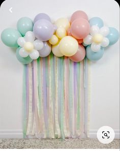 a bunch of balloons that are on top of a wall next to a curtain with streamers