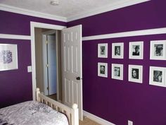 a bedroom painted in purple and white with pictures hanging on the wall above the bed