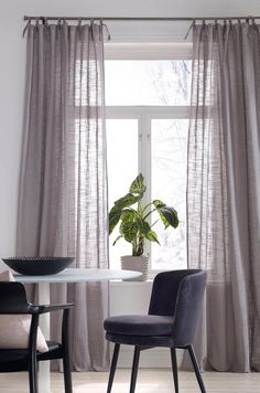 a dining room table with two chairs and a potted plant in the window sill