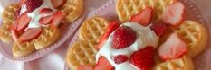 two waffles with strawberries and whip cream on them