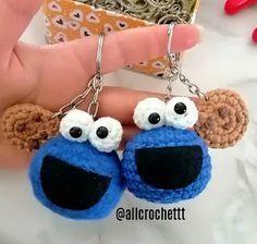 the hand is holding two small crocheted keychains with googly eyes