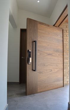 an open wooden door in the middle of a room with white walls and flooring