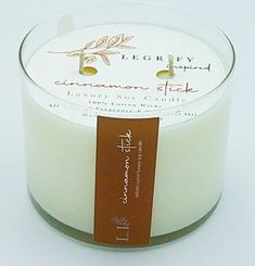 a candle with a label on it sitting in front of a white tablecloth background