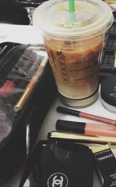 a cup of coffee sitting on top of a table next to makeup and other items