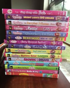 a stack of children's books sitting on top of a wooden table next to a window