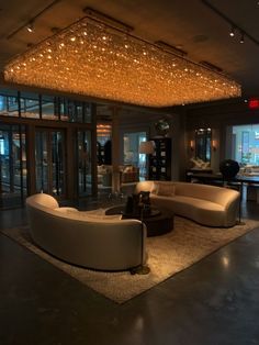 a living room filled with furniture and a chandelier hanging from the ceiling above it