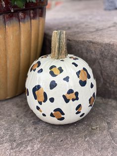 a painted pumpkin sitting next to a potted plant