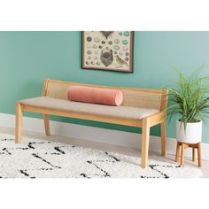 a wooden bench sitting on top of a white rug next to a potted plant