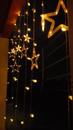 some lights hanging from the side of a building with stars attached to it's sides