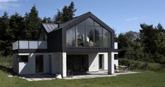 a modern house in the middle of a grassy area with trees and grass around it