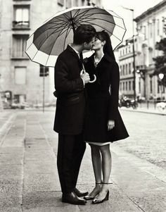 a man and woman kissing under an umbrella