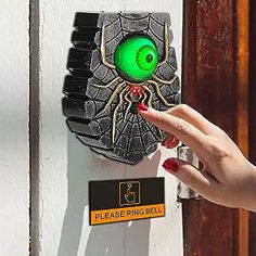 a woman's hand pointing at a door handle with an eyeball on it