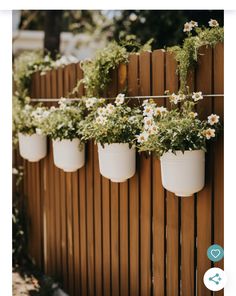 four white flower pots hanging from a wooden fence