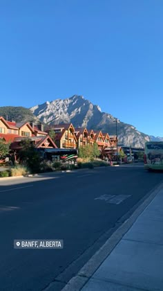 an empty street in front of some mountains with houses on each side and the words banff, alberita written below