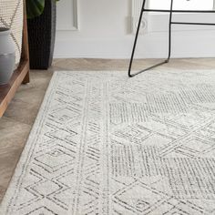 a white rug on the floor in front of a chair and potted plant next to it