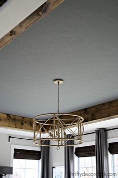 a chandelier hanging from the ceiling in a living room with curtains and windows